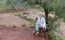 Roxy Cox visiting Ethiopean rock hewn church in Lalibela, Ethiopia, seated under a tree