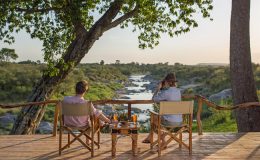 Rekero Camp couple having drinks by the river Mara conservancies